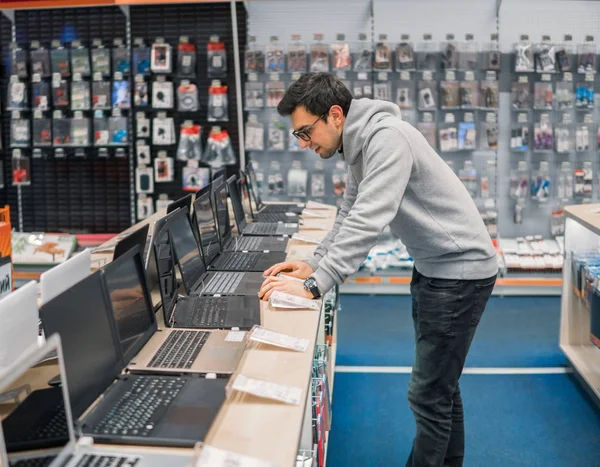 modern male customer choosing laptop in the computer shop
