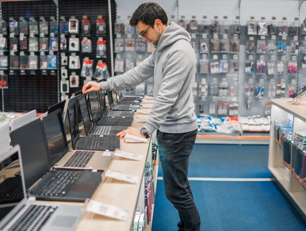 Cliente masculino moderno escolhendo laptop na loja de computadores — Fotografia de Stock