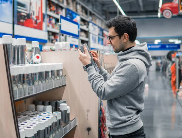 El cliente masculino compra pintura en aerosol puede en el supermercado — Foto de Stock