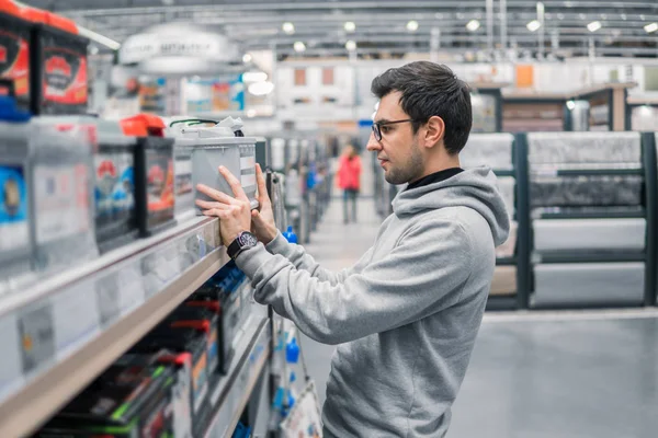 Cliente masculino inteligente que compra la batería del coche n el supermercado del coche — Foto de Stock