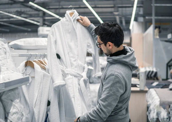 Masculino cliente inspecionar e comprar roupão de banho no supermercado . — Fotografia de Stock