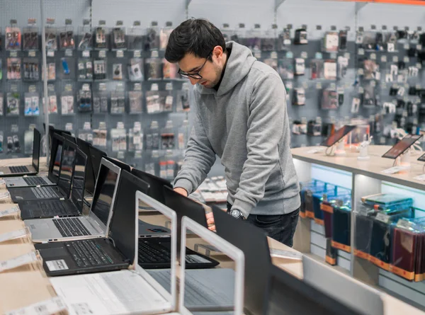 Cliente masculino moderno escolhendo laptop na loja de computadores — Fotografia de Stock