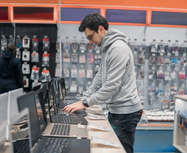 Cliente masculino moderno que elige el ordenador portátil en la tienda de computadoras — Foto de Stock