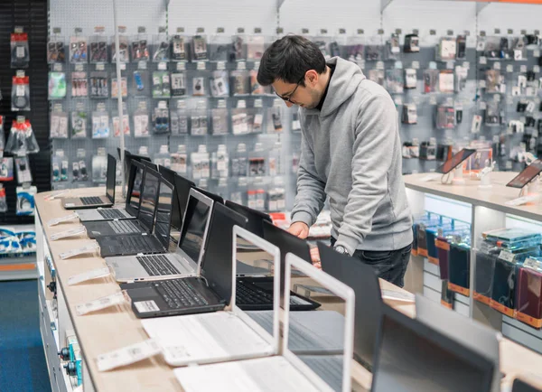 Cliente masculino moderno escolhendo laptop na loja de computadores — Fotografia de Stock