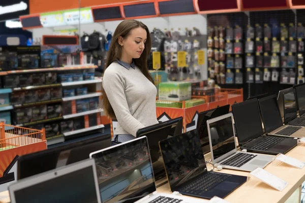 Cliente femenino moderno que elige el ordenador portátil en la tienda de computadoras . — Foto de Stock