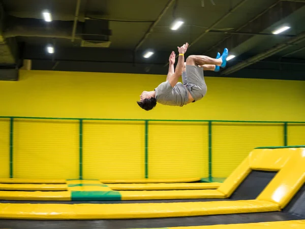 Прыгун на батуте выполняет акробатические упражнения на батуте — стоковое фото