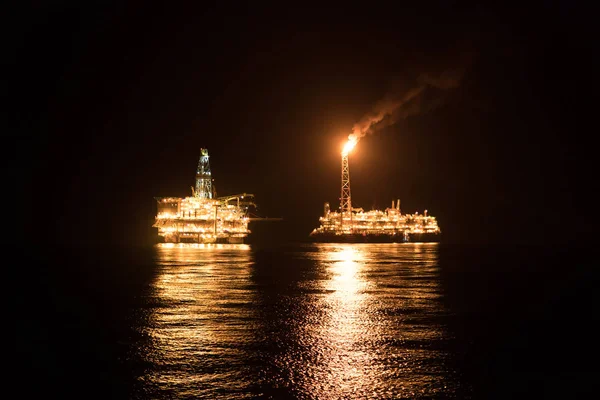 FPSO tanker vessel near Oil Rig at night. Offshore oil and gas industry