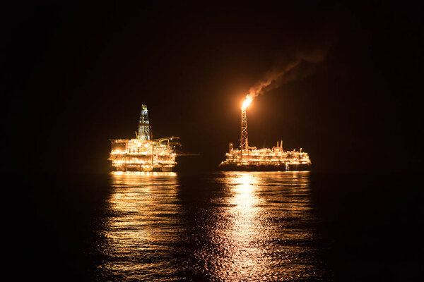 FPSO tanker vessel near Oil Rig at night. Offshore oil and gas industry