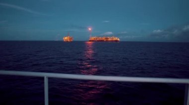 FPSO tanker gemisi yakınındaki petrol sondaj platformu platformu. Offshore petrol ve gaz endüstrisi. İşaret fişeği dumanla yanıyor. İkmal gemisi görüntülemek