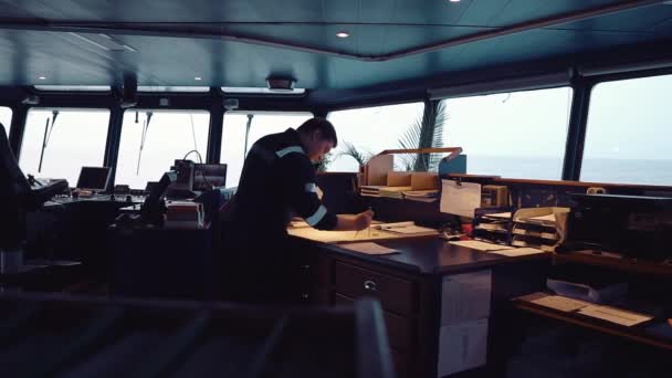 Oficial de navegação dos fuzileiros navais durante a navegação na ponte. Ele faz correção de gráfico — Vídeo de Stock