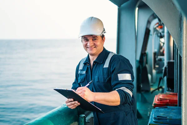 Oficial de convés no convés de embarcação ou navio offshore, usando equipamento de proteção individual EPI. Ele preenche a lista de verificação. Papelada no mar — Fotografia de Stock