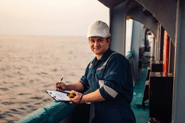 Oficial de convés no convés de embarcação ou navio offshore, usando equipamento de proteção individual EPI. Ele preenche a lista de verificação. Papelada no mar — Fotografia de Stock