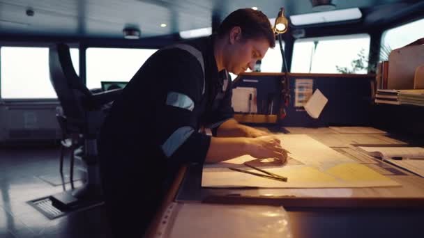 Oficial de navegación de la Marina durante la guardia de navegación en Bridge. Él hace corrección de cartas — Vídeos de Stock