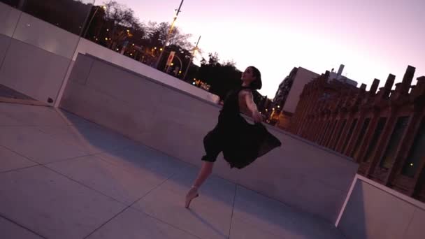 Jeune ballerine professionnelle en robe noire danse en plein air — Video