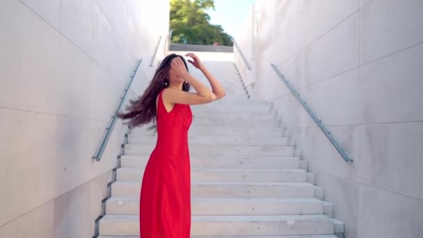 Όμορφη γυναίκα με κόκκινο κομψό φόρεμα. Λευκό αστικό φόντο — Αρχείο Βίντεο