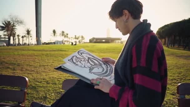 Modern ung snygg manlig målare rita skisser i parken — Stockvideo