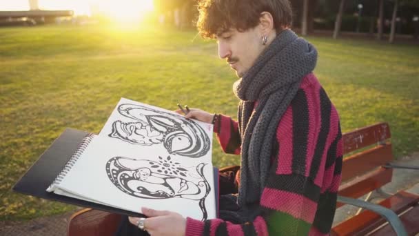 Moderne jonge stijlvolle mannelijke schilder tekening schetsen in het park — Stockvideo
