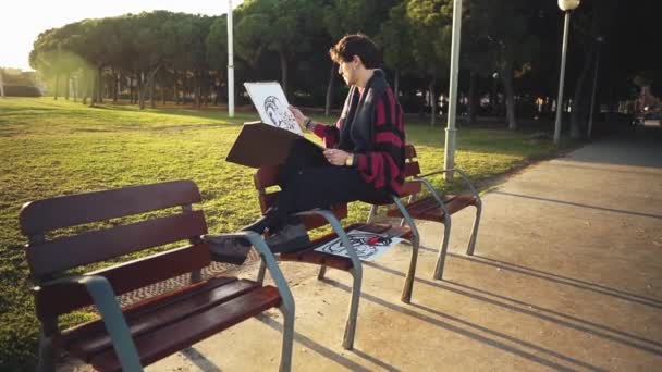 Modern young stylish male paint artist drawing sketches in park — Stock Video