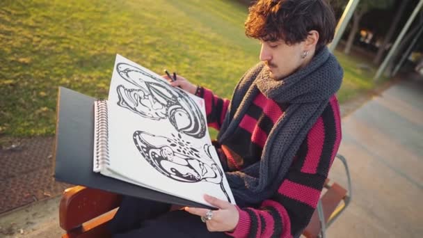 Moderne jonge stijlvolle mannelijke schilder tekening schetsen in het park — Stockvideo