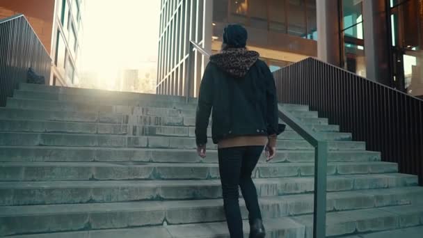 Retrato de hipster de pelo largo caminando por la calle en la ciudad moderna — Vídeos de Stock