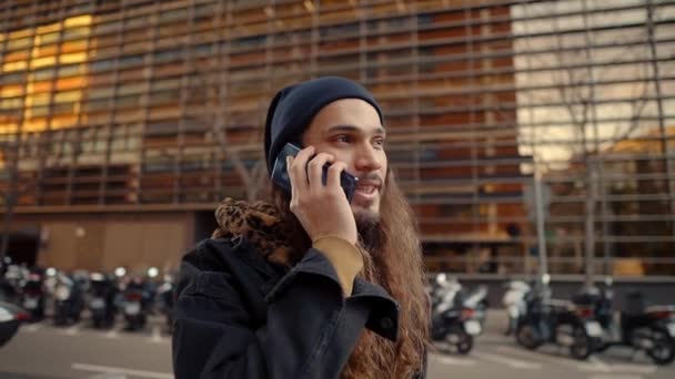 Retrato de hipster de pelo largo caminando por la calle en la ciudad moderna — Vídeo de stock