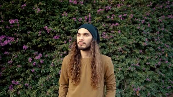 Portrait of long haired hipster walking near parkt in modern city — Stock Video