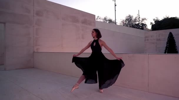 Young professional ballerina in black dress is dancing outdoors — 비디오