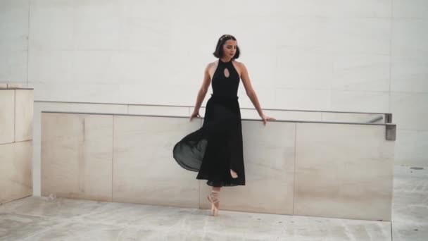 Young professional ballerina in black dress is dancing outdoors — 비디오