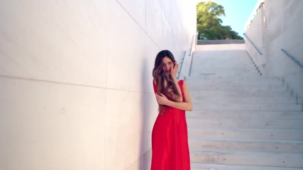 Mooie vrouw in rode elegante jurk. Stedelijke witte achtergrond — Stockvideo