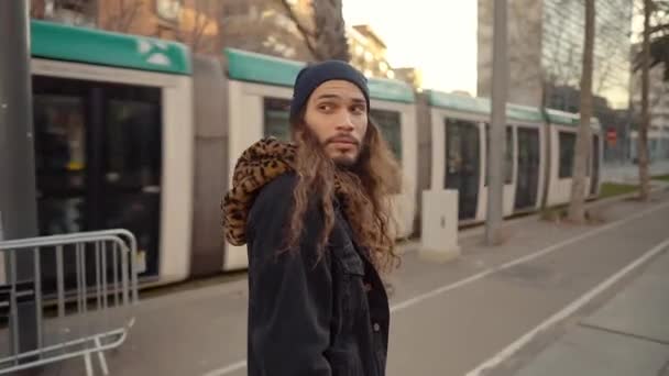 Retrato de hipster de pelo largo caminando por la calle en la ciudad moderna — Vídeo de stock