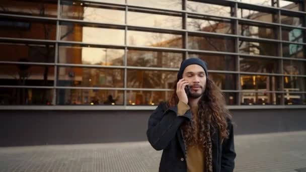 Retrato de hipster de pelo largo caminando por la calle en la ciudad moderna — Vídeo de stock