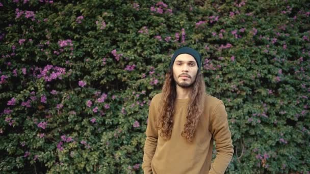 Portrait of long haired hipster walking near parkt in modern city — Stock Video