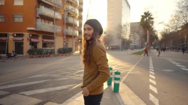 Modern şehirde sokakta yürüyen uzun saçlı hippi portresi.