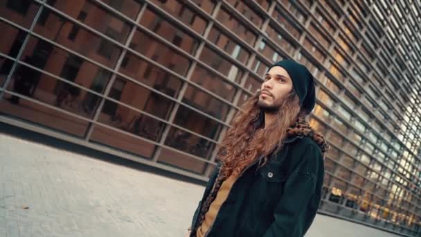 Portrait de hipster aux cheveux longs marchant dans la rue dans la ville moderne — Video