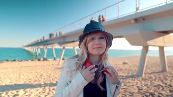 Femme marchant le long de la belle plage au coucher du soleil avec écouteurs — Video