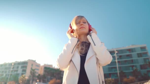 Donna che cammina lungo la bellissima spiaggia al tramonto con le cuffie — Video Stock