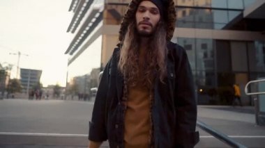 Modern şehirde sokakta yürüyen uzun saçlı hippi portresi.