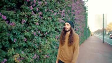 Modern şehrin parkında yürüyen uzun saçlı hippi portresi.