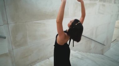 Siyah elbiseli genç profesyonel balerin dışarıda dans ediyor.