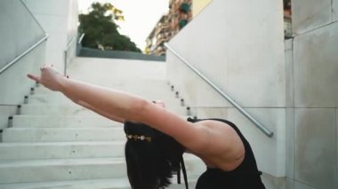 Siyah elbiseli genç profesyonel balerin dışarıda dans ediyor.