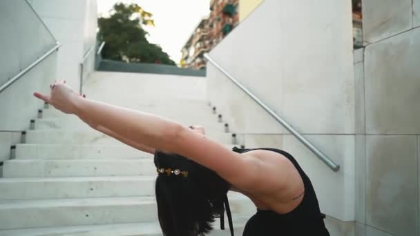 Молода професійна балерина в чорній сукні танцює на відкритому повітрі — стокове відео