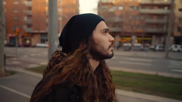 Retrato de hipster de pelo largo caminando por la calle en la ciudad moderna — Vídeo de stock