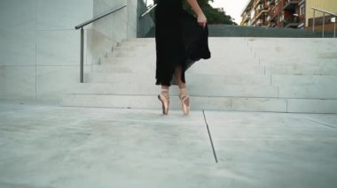 Siyah elbiseli genç profesyonel balerin dışarıda dans ediyor.