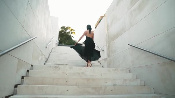 Young professional ballerina in black dress is dancing outdoors — Stock Video