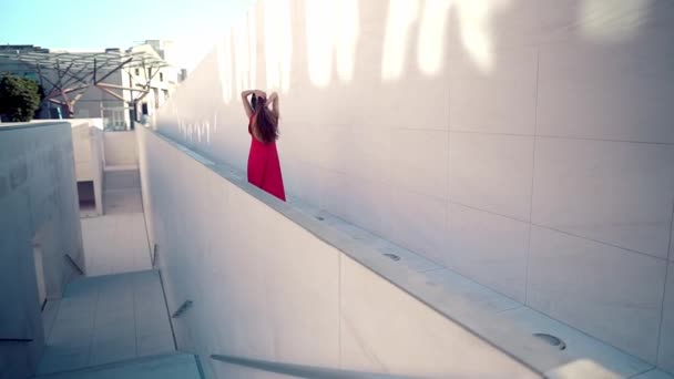 Hermosa mujer en vestido elegante rojo. Fondo blanco urbano — Vídeo de stock