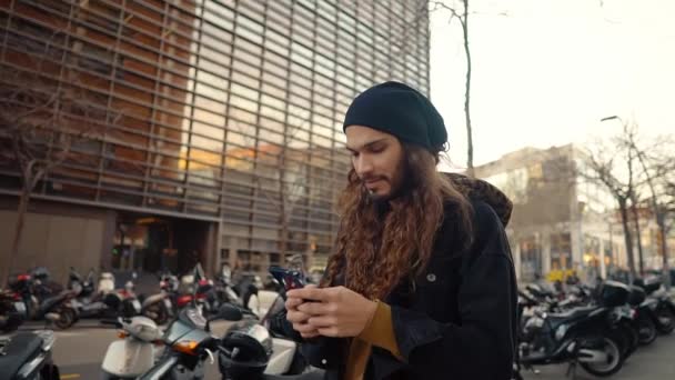 Retrato de hipster de pelo largo caminando por la calle en la ciudad moderna — Vídeo de stock