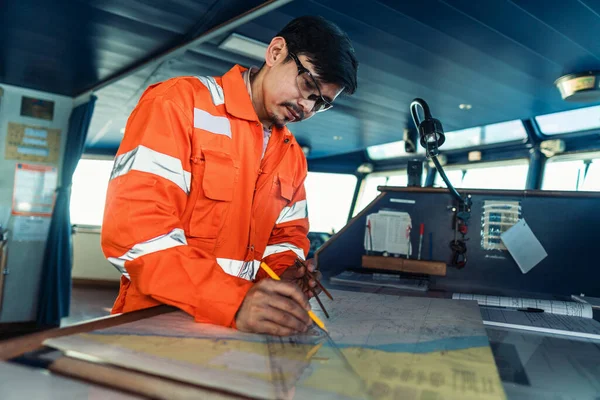 Oficial de convés filipino na ponte de navio ou navio. Ele está a traçar posição no gráfico. — Fotografia de Stock