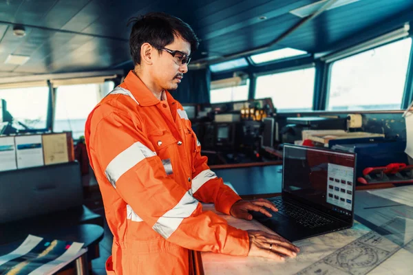 Filippijnse dekofficier op brug van schip of schip. Hij gebruikt laptop, elektronisch papierwerk op zee. — Stockfoto