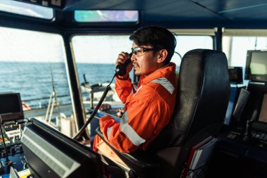 Filipinli güverte subayı gemi ya da gemi köprüsünde. GMDSS VHF radyosunda konuşuyor.