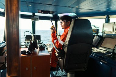 Filipinli güverte subayı gemi ya da gemi köprüsünde. GMDSS VHF radyosunda konuşuyor.